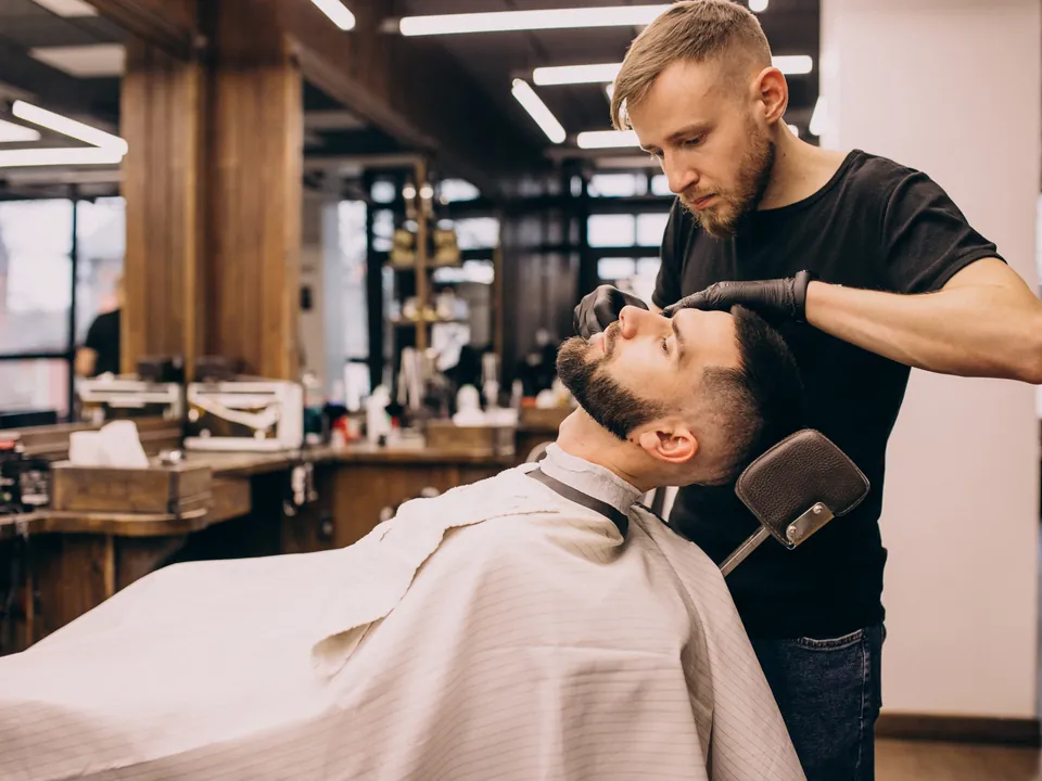 A barber trimming a client's beard